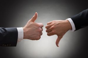 Close-up Of Two Businesspeople Hands Showing Thumb Up And Thumb Down Sign